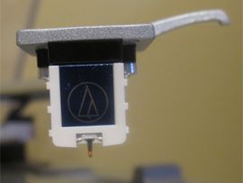Close-up photo shows the cartridge and stylus on the Audio-Technica AT-LP120-USB.